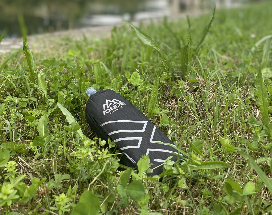 Une gourde running à main posée dans l'herbe avec un fond flou